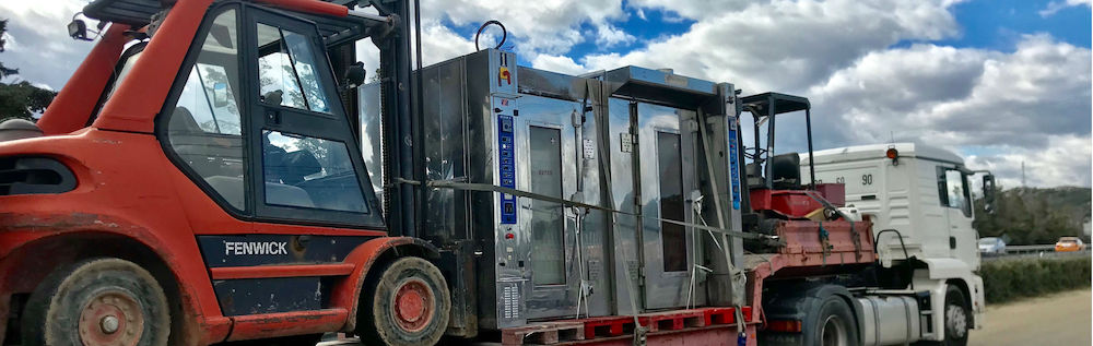 Four rotatifs de boulangerie d'occasion sur un camion porte char avec un chariot fenwick 