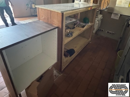 Arrière du comptoir de réception d’occasion : étagères ouvertes dans le module central, extension gauche avec caisson en mélaminé 